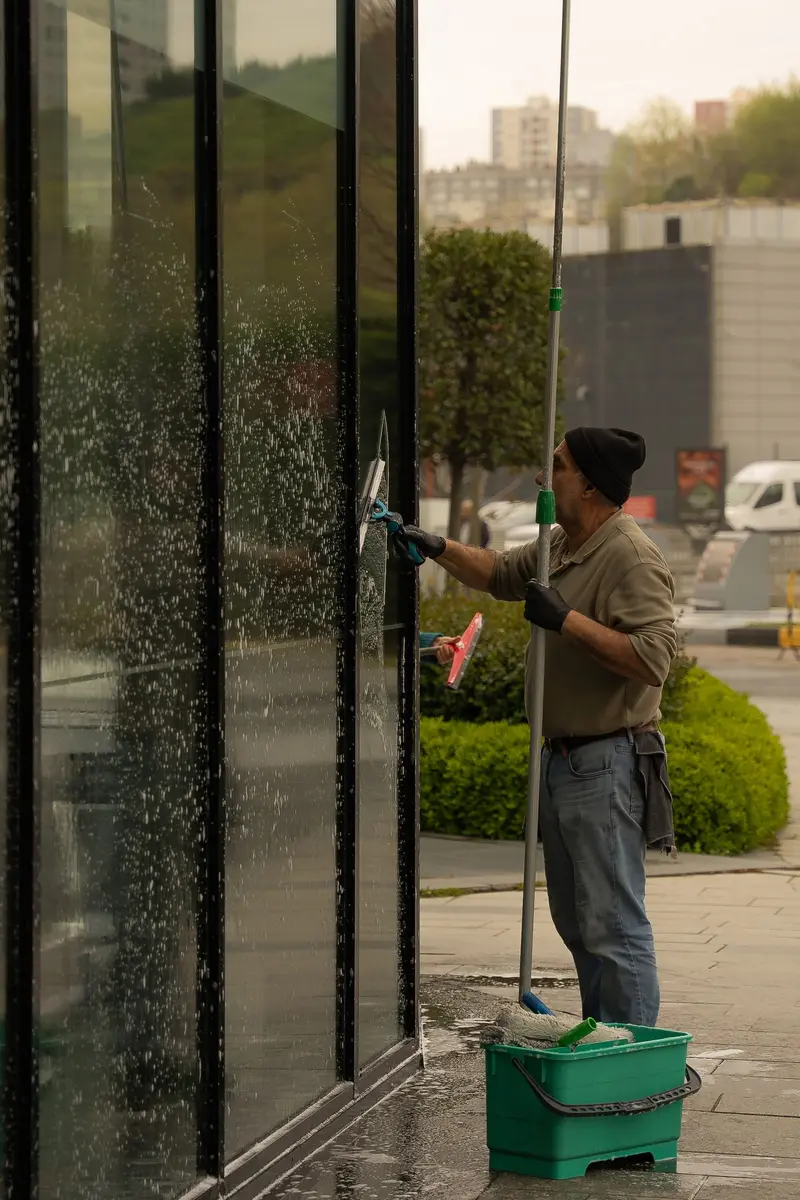 Glasreinigung: Fensterputzer zieht eine Glasfassade mit dem Abzieher ab